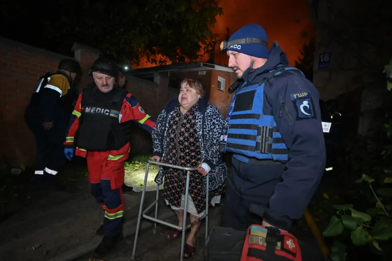 I paramedici ucraini aiutano un residente sul luogo di un attacco di droni russi a Kharkiv, alla fine del 27 ottobre 2026, nel mezzo dell'invasione russa dell'Ucraina. (Foto di SERGEY BOBOK/AFP)