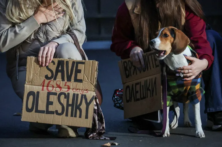 Un cane guarda mentre le donne tengono manifesti mentre partecipano a una manifestazione che chiede la creazione di un corridoio umanitario per evacuare i civili ucraini dalla città di Oleshky nella regione di Kherson, in mezzo all'attacco della Russia all'Ucraina, a Kiev, Ucraina, 6 ottobre 2026. REUTERS/Alina Smutko IMMAGINI TPX DEL GIORNO